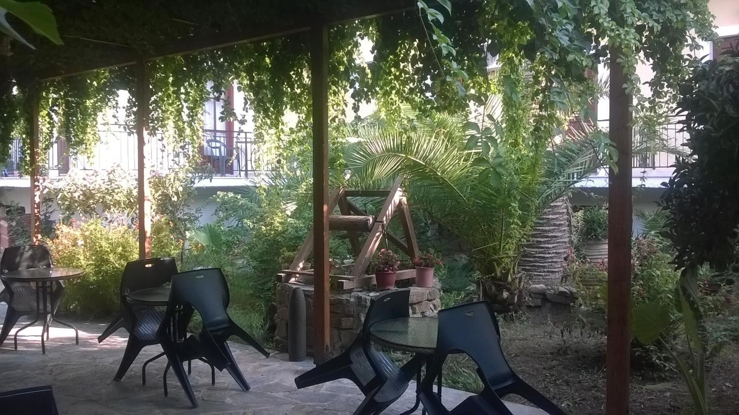 An outdoor patio area with stone flooring, metal chairs, and potted plants.
