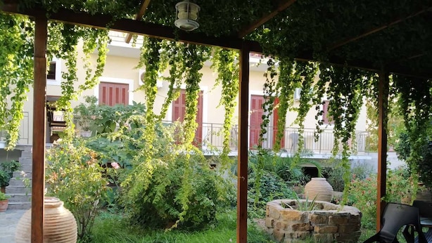 Un espacio al aire libre cubierto con suelo de piedra, plantas en macetas y una construcción de piedra.