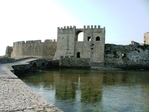Un puente de piedra histórico que conduce a un castillo fortificado con foso.