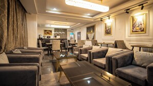 A modern hotel lobby with plush seating, a reception desk, and a chandelier. - Vynedresa Hotel (Abuja)