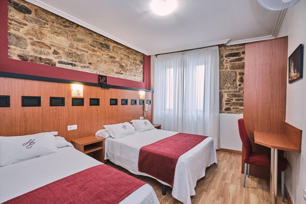 Une chambre d’hôtel avec deux lits, un bureau et une chaise.