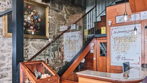 Un hall d’hôtel avec un comptoir d’accueil en bois, un escalier et une carte accrochée au mur.