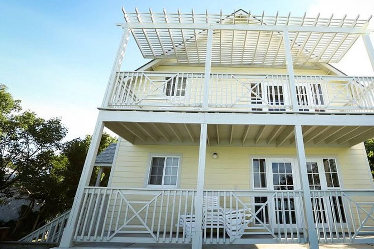 A two-story building with a balcony on each floor, featuring white railings and a flat roof.