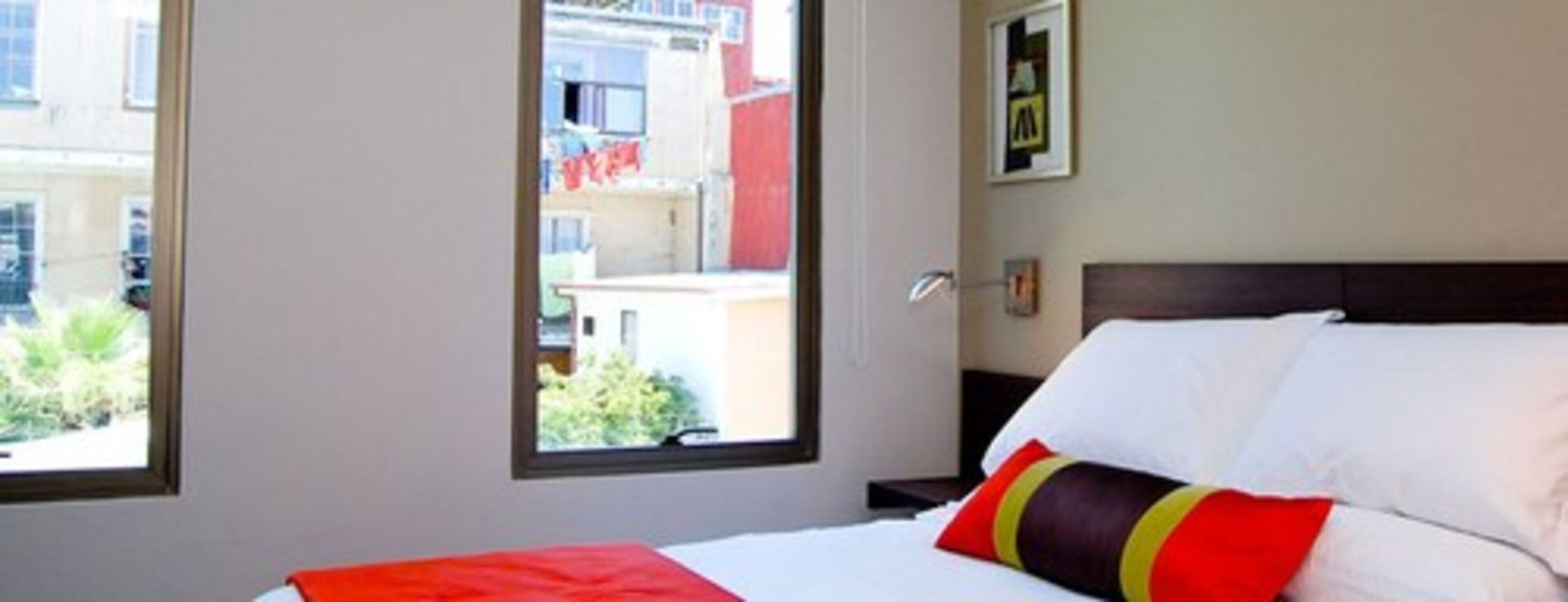 Habitación de hotel con una cama, una ventana y vistas a edificios.