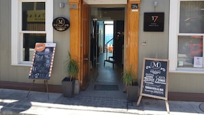 Entrada de hotel con un arco de madera, un letrero que dice 'Hotel Boutique 17' y un menú en una pizarra fuera.