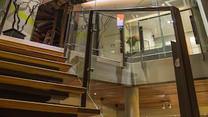 Un interior moderno con una escalera de barandilla de cristal que desciende a un nivel inferior.