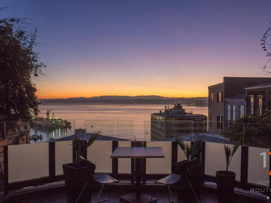 Een terras met een tafel en stoelen met uitzicht op het water bij zonsondergang.