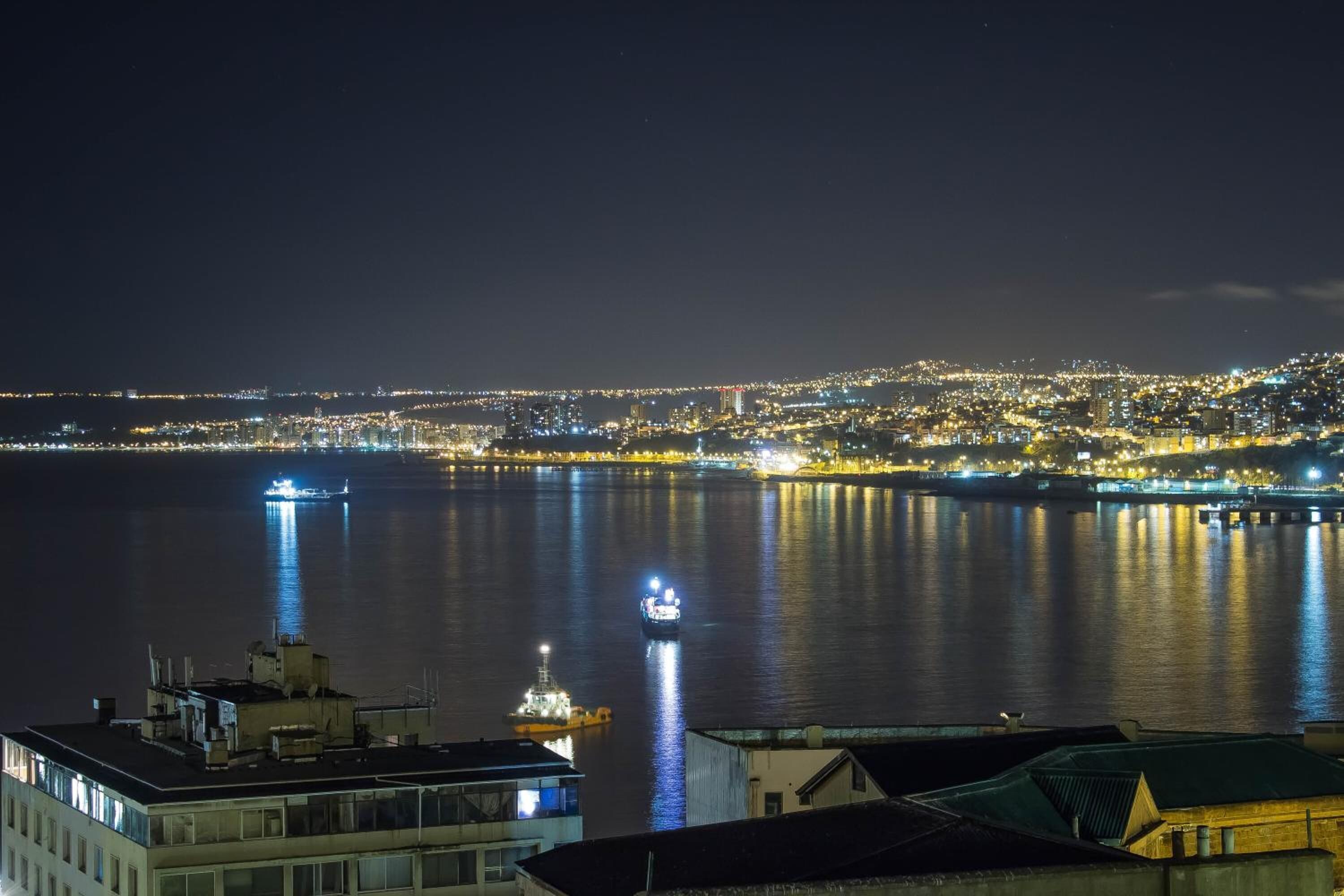 Een nachtelijk stadsgezicht met een rustige rivier die de lichtjes van de stad weerspiegelt.