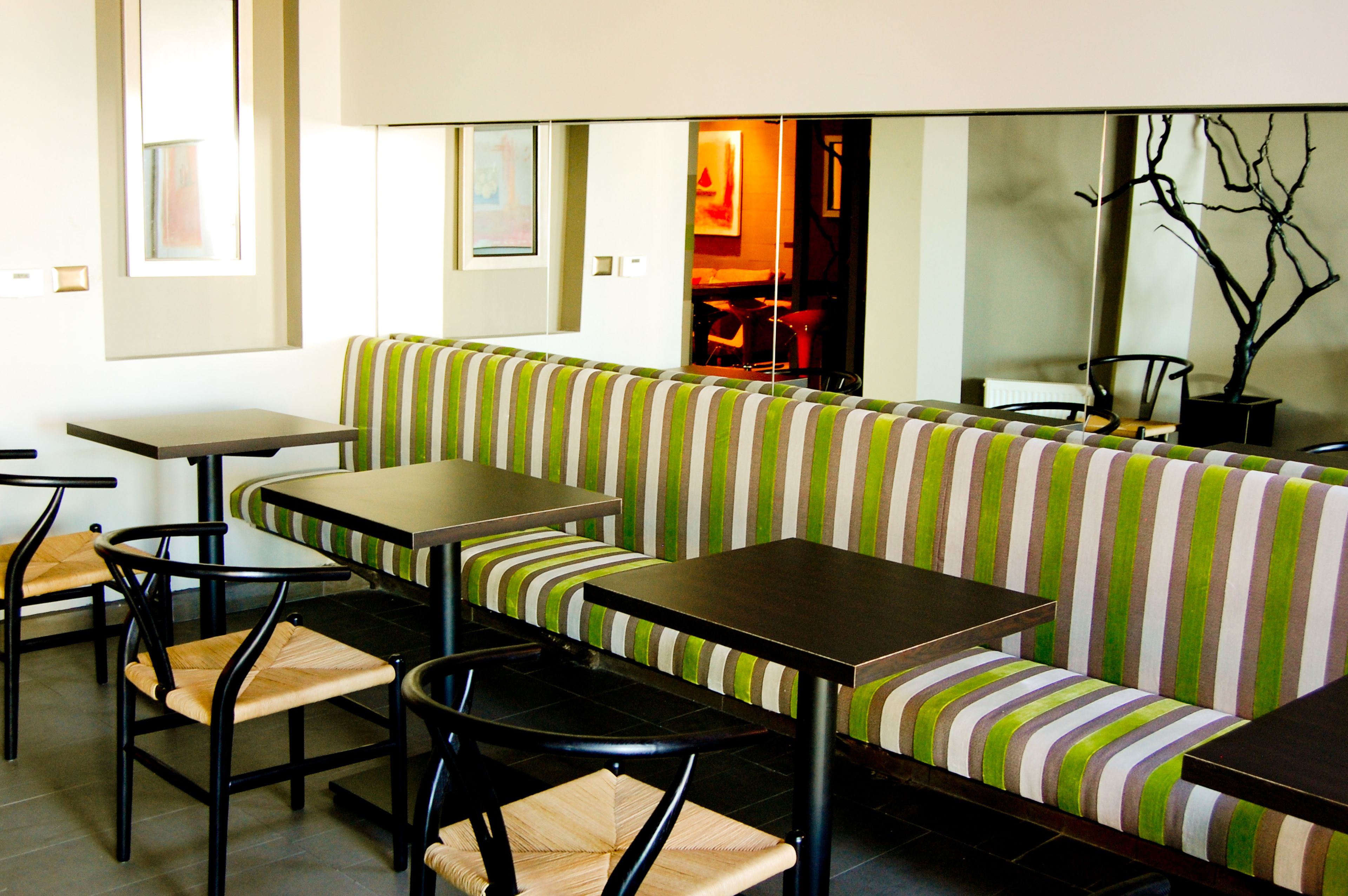 A restaurant with striped green and white seating, black tables, and chairs.