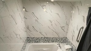 Um banheiro moderno com banheira livre, pia pequena e área de chuveiro.