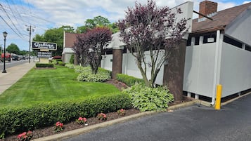 A well-maintained lawn, a sign for 'Gabino Catering Hall', and a building with a brick chimney.