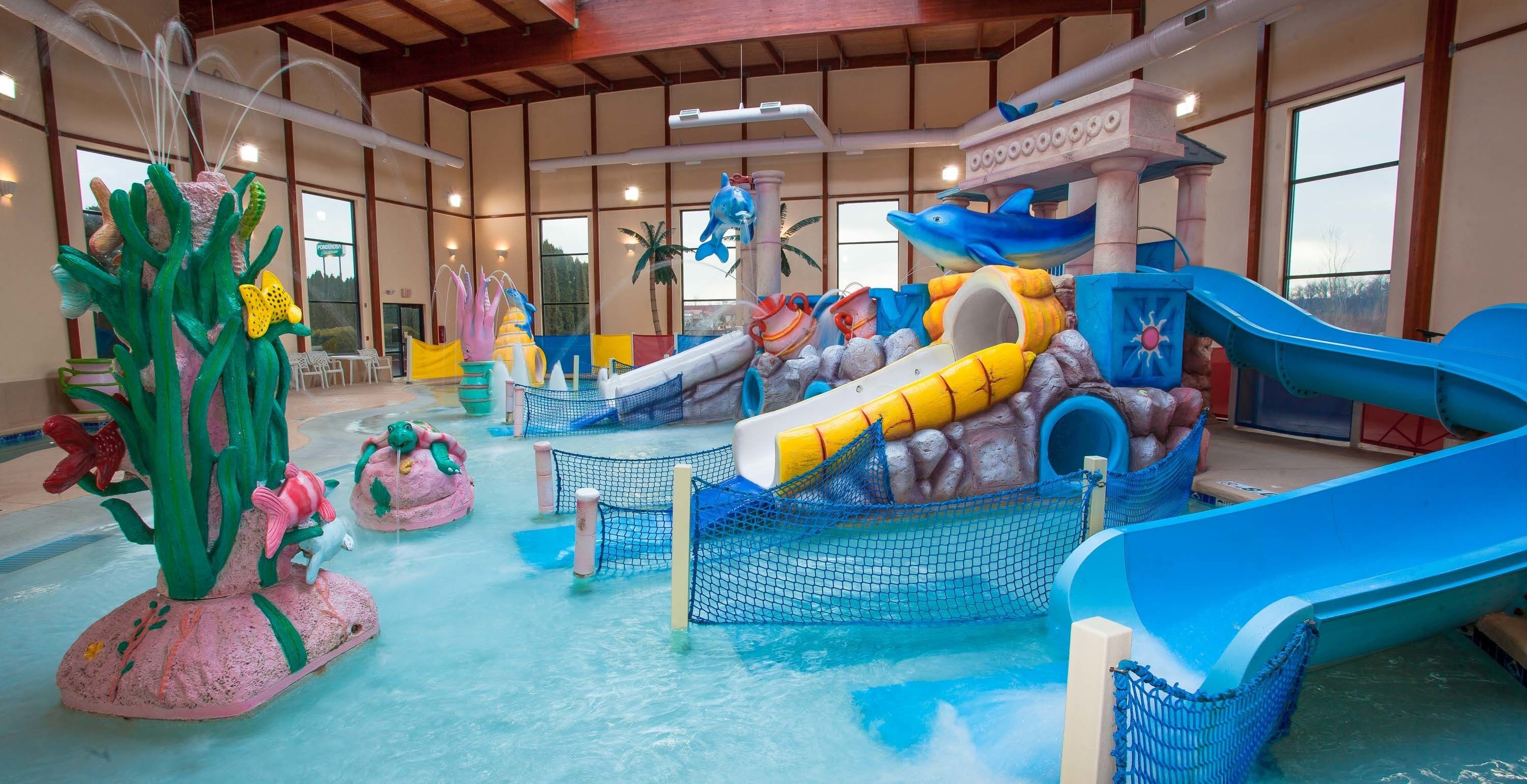 Un parc aquatique intérieur doté de toboggans, d’une piscine à vagues et d’une grande plante décorative.