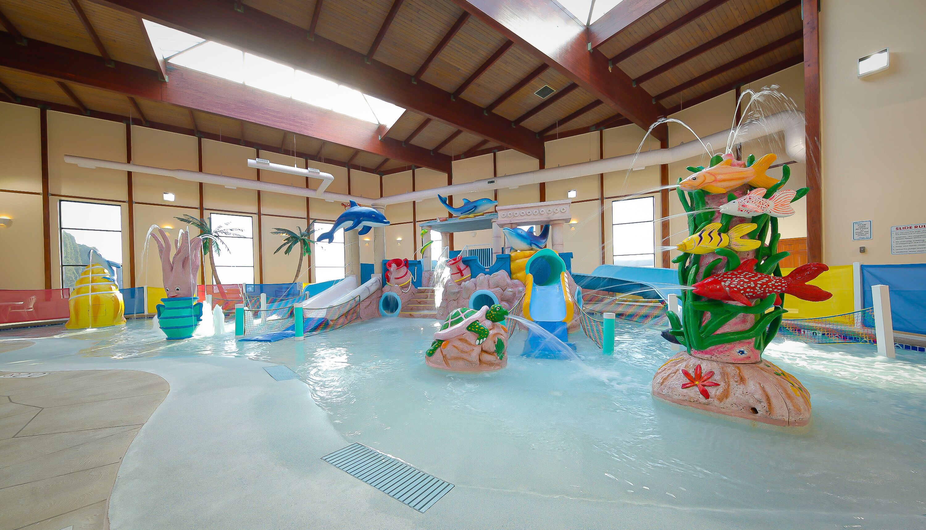 An indoor water park with slides, water features, and a large pool area.