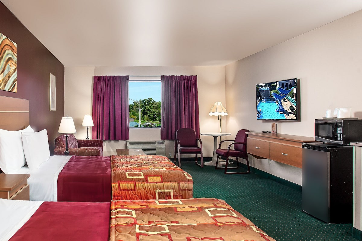 Habitación de hotel con dos camas, un escritorio, un televisor y vistas al exterior.