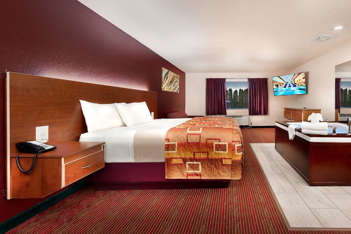 Habitación de hotel con una cama grande, un escritorio, una tocador y un televisor.