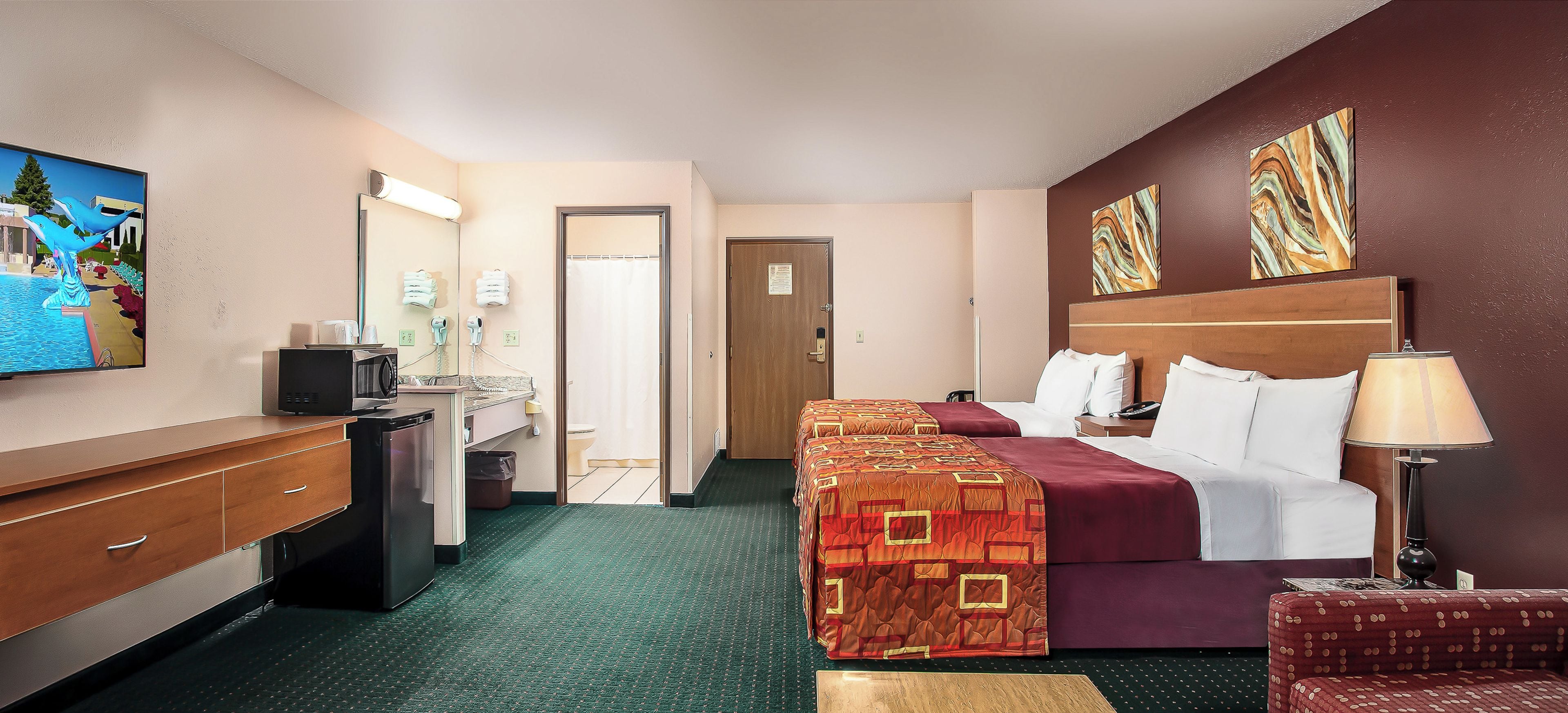 A hotel room with a bed, a desk, a chair, a television, and artwork on the walls.