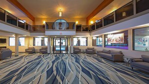 Un hall d’entrée spacieux au design moderne, agrémenté d’un tapis à motifs, de sièges confortables et d’une grande entrée.