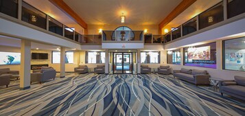 A spacious lobby with a modern design, featuring a patterned carpet, comfortable seating, and a large entrance.