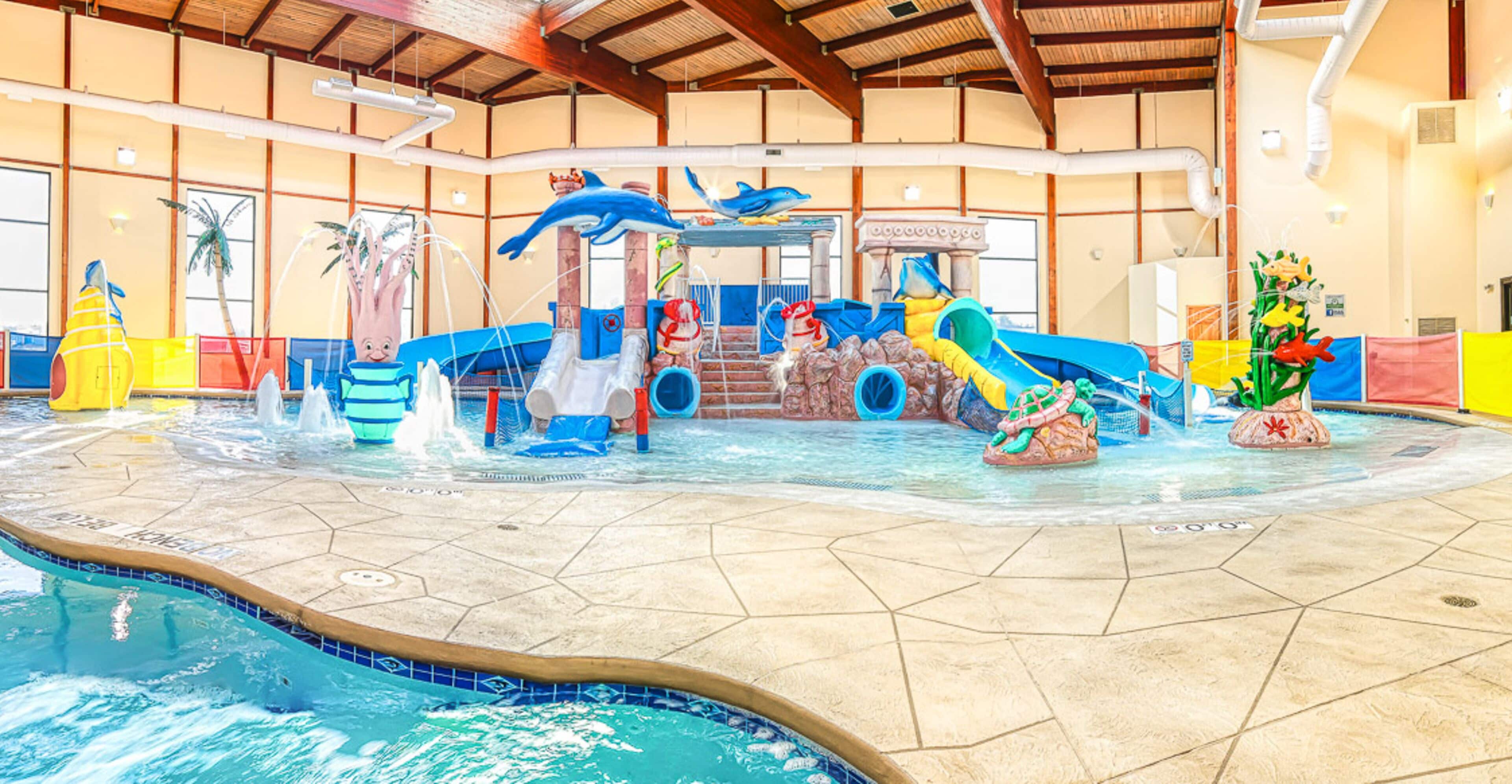 An indoor water park with slides, water features, and a pool.