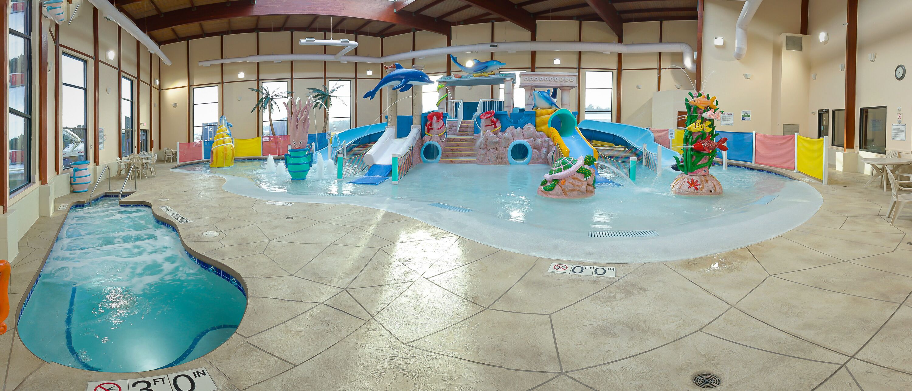 Parque acuático interior con toboganes, una máquina de olas y una piscina.