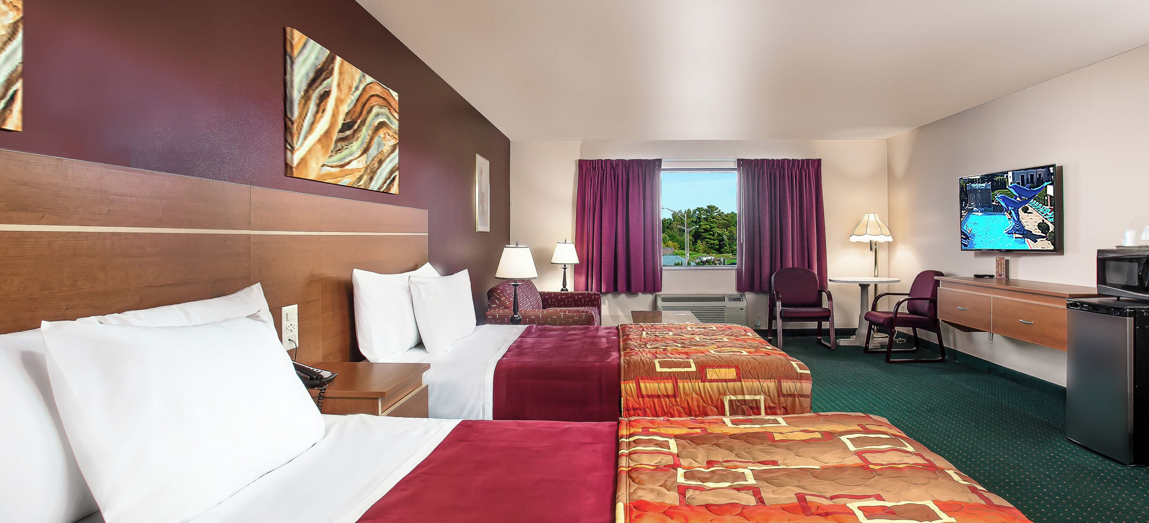Ein Hotelzimmer mit Bett, Schreibtisch, Fernseher und Blick ins Freie.