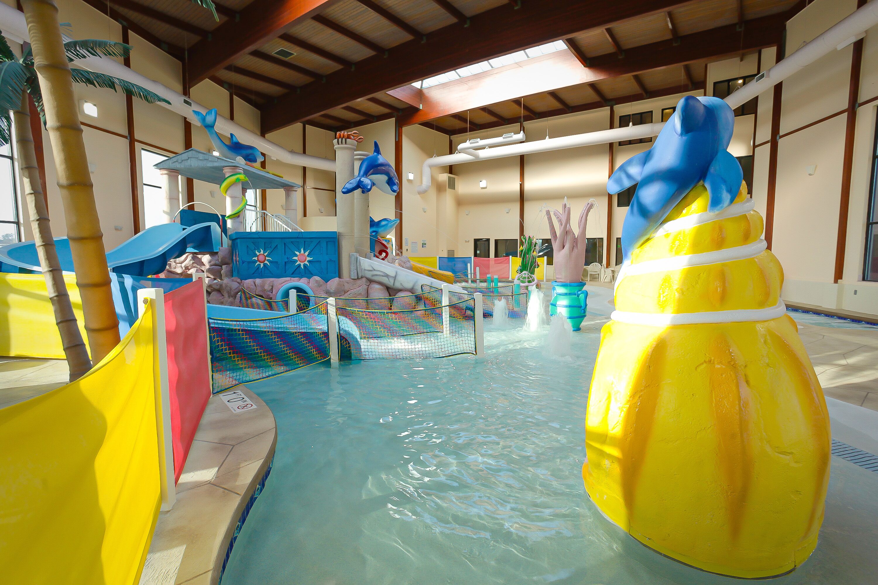 An indoor water park with slides, water features, and a pool.