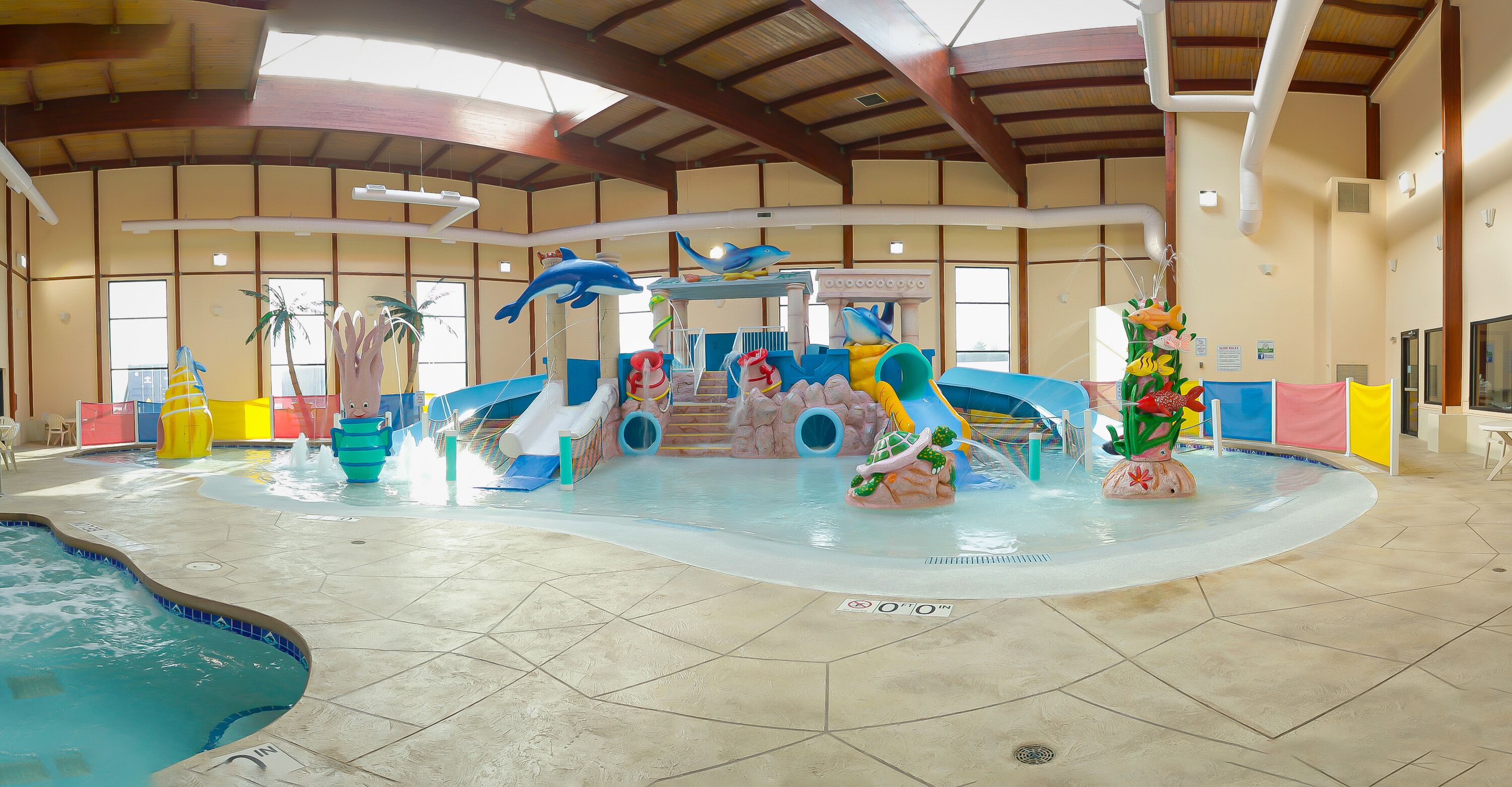 An indoor water park with slides, water features, and a pool.