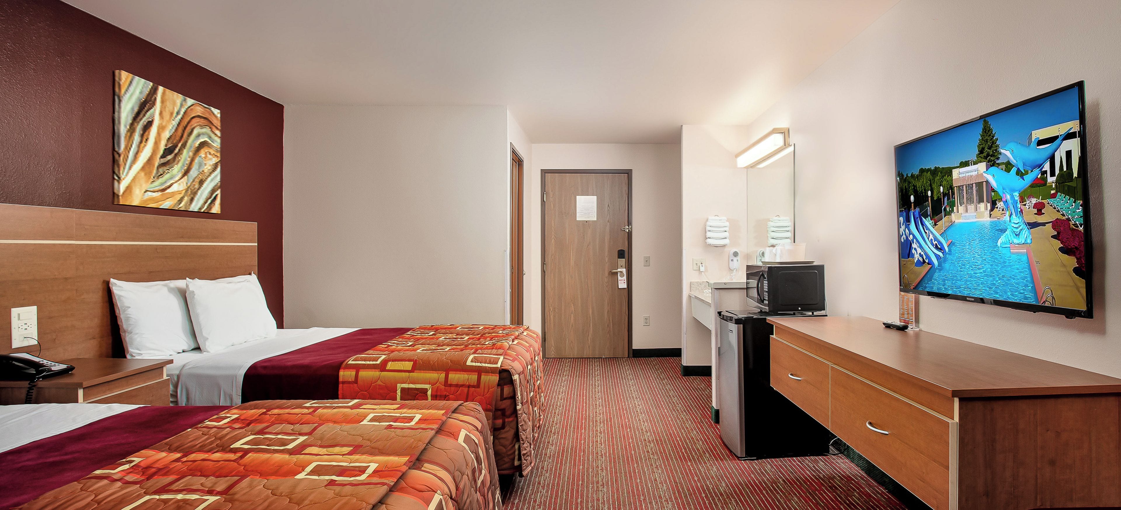 Habitación de hotel con dos camas, un escritorio, un televisor y un cuadro en la pared.