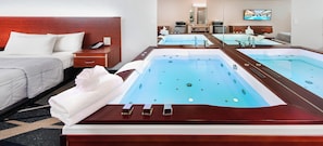 Een hotelkamer met een grote pooltafel, een bed, een nachtkastje met telefoon en een televisie aan de muur.