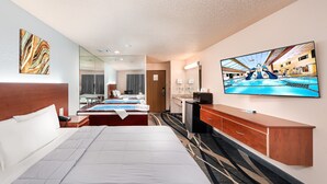 Une chambre d’hôtel dotée d’un grand lit, d’une télévision, d’un bureau et d’une salle de bain visible à travers une paroi en verre.