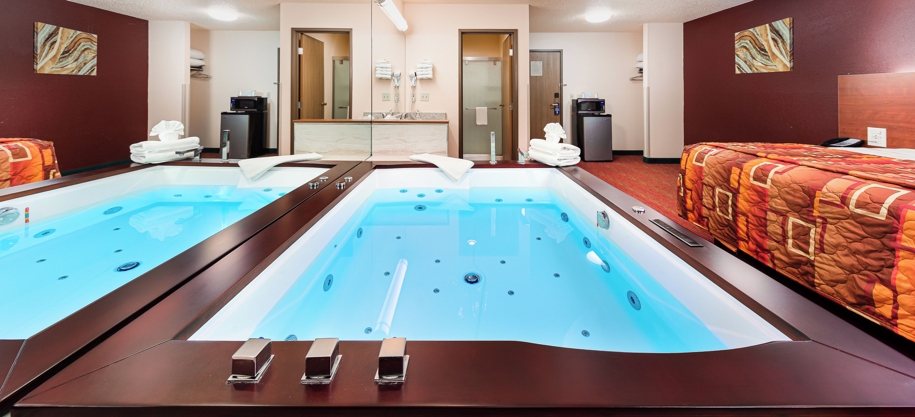 Une chambre d’hôtel avec une grande baignoire, un lit et un bureau équipé d’un ordinateur.