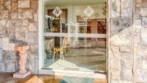 Una entrada con pared de piedra, puerta de cristal, una silla de madera y una mesita.