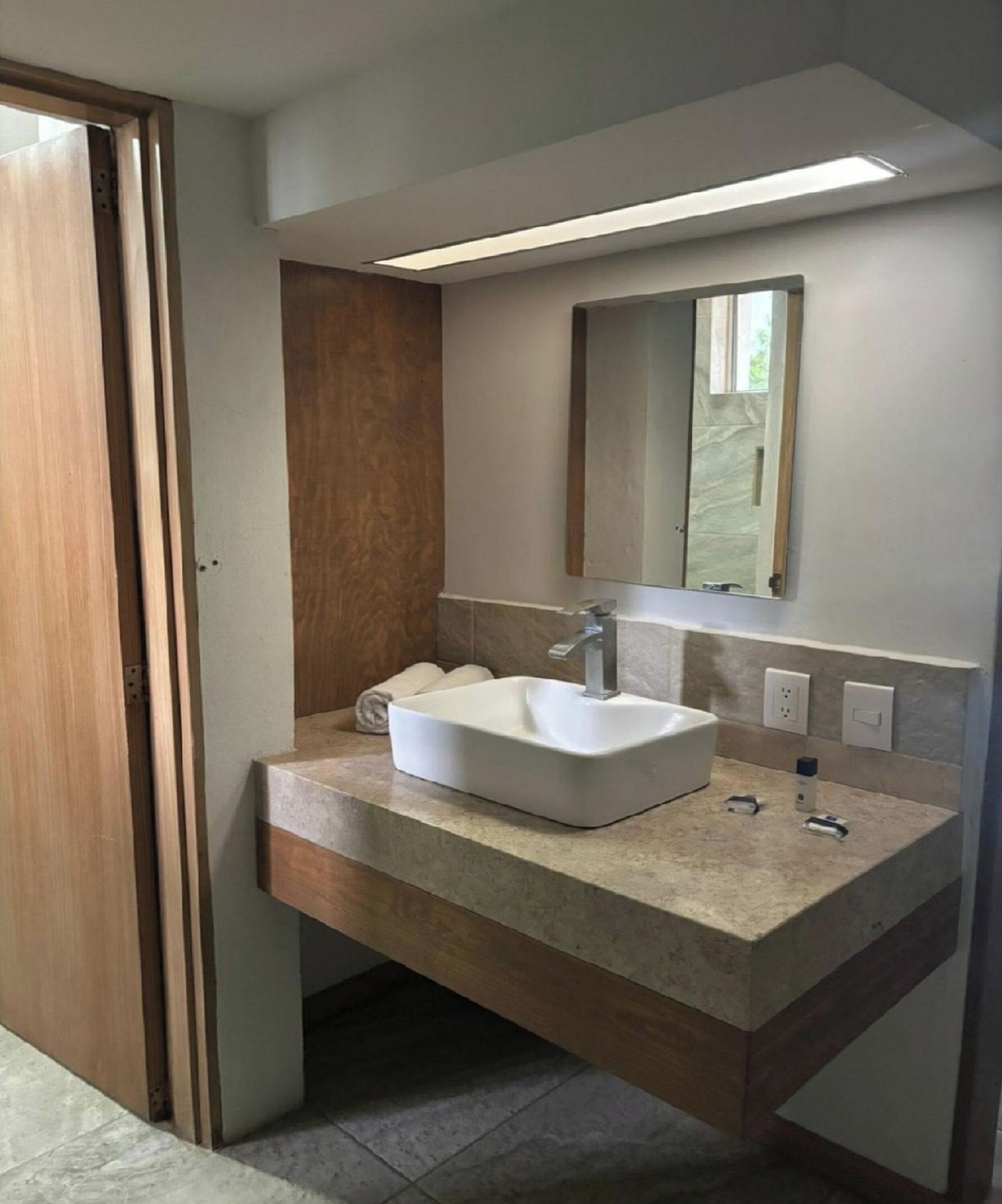 A bathroom with a white sink, a mirror, and a wooden door.