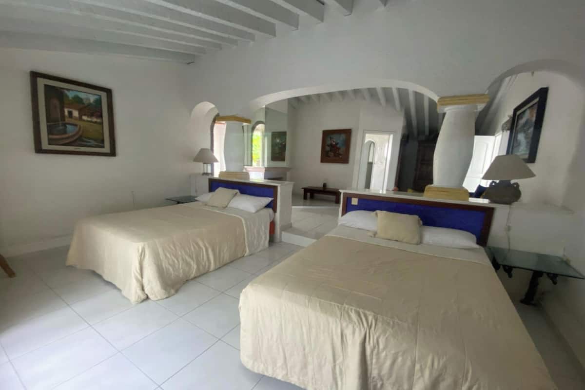 A hotel room with two beds, white walls, and a large mirror.