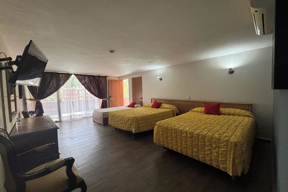 A hotel room with two beds, a desk, and a TV.