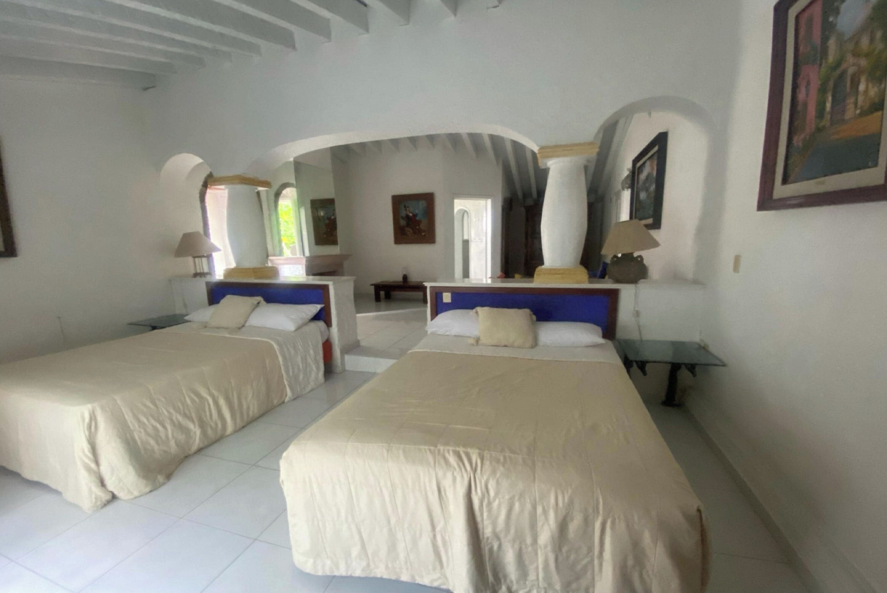 Une chambre d’hôtel avec deux lits, une petite table, une lampe et un tableau au mur.