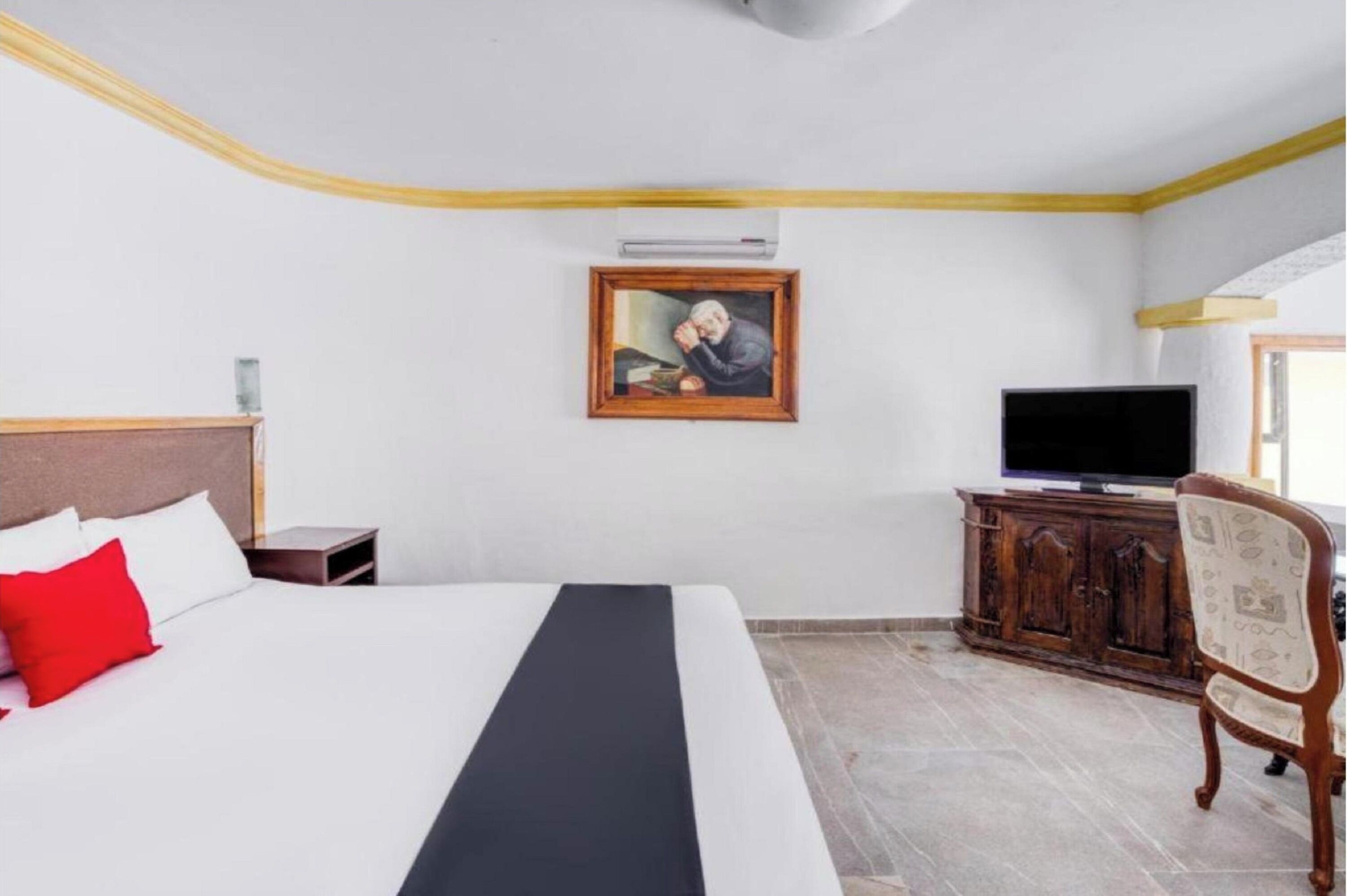 Une chambre d’hôtel avec un lit, une télévision, une armoire en bois et un tableau au mur.