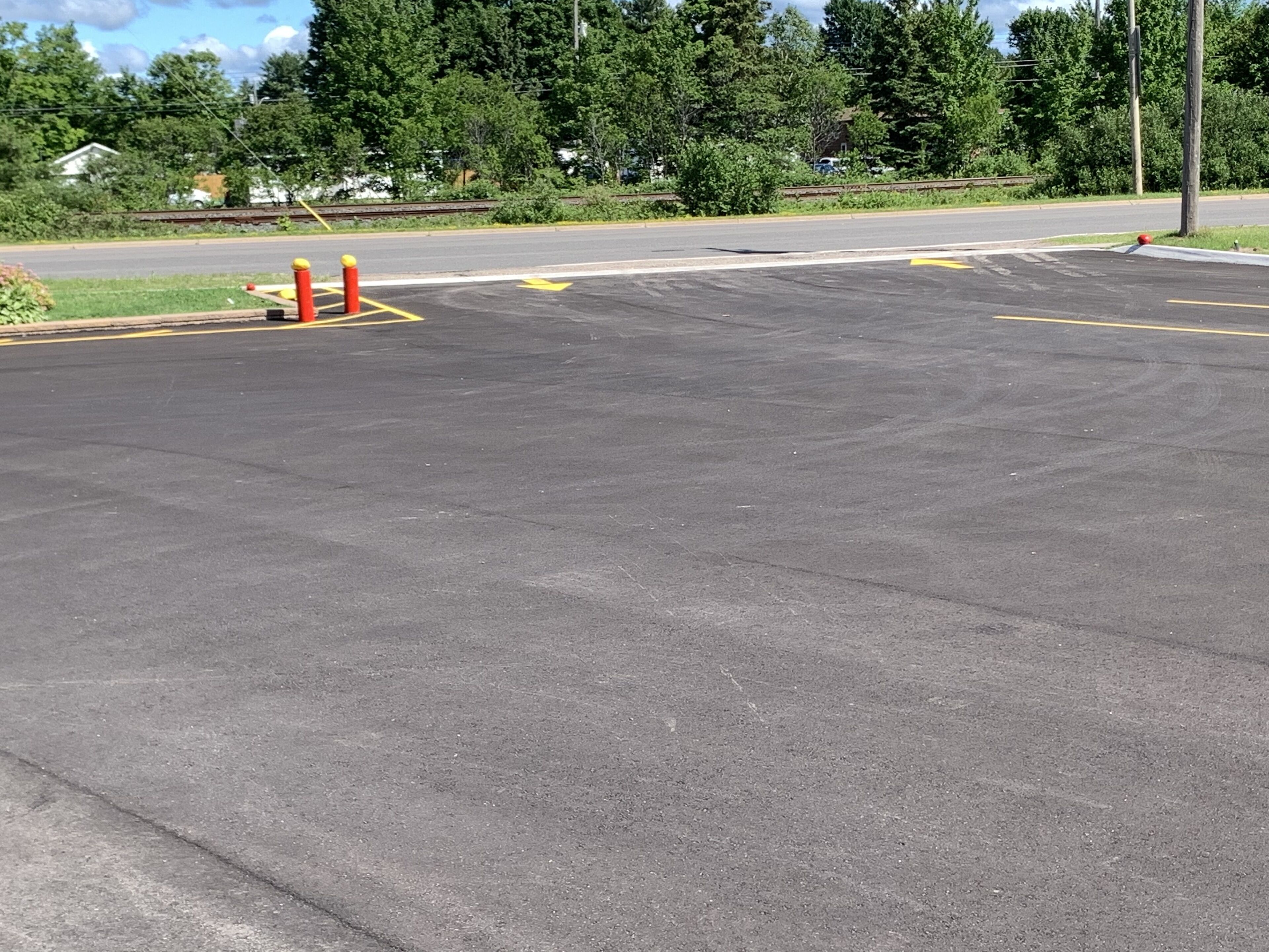 Um estacionamento com vagas demarcadas e uma seta amarela indicando direção no asfalto.