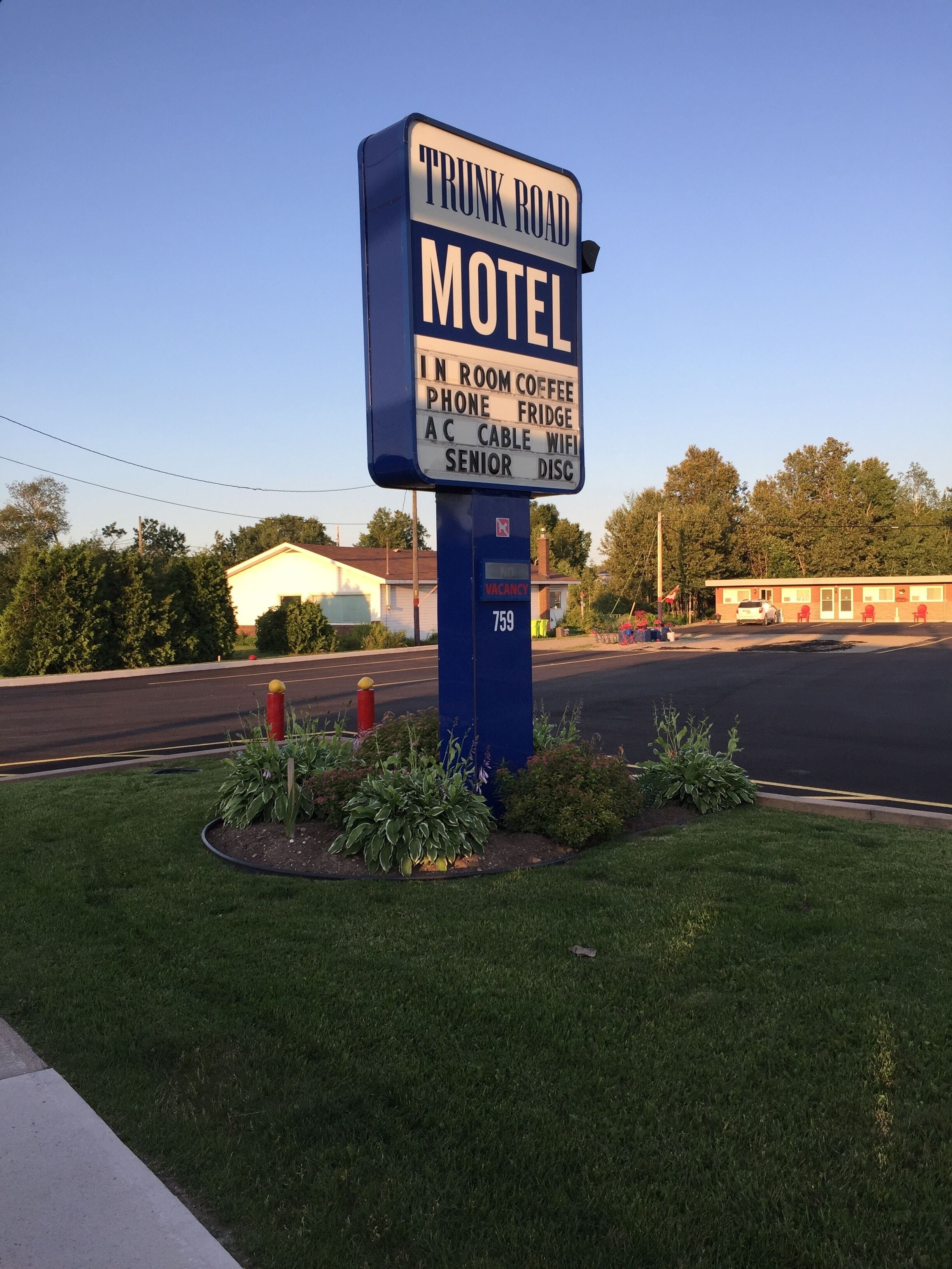 A motel sign with amenities including in-room coffee, phone, fridge, AC, cable, wifi, and senior discount.