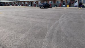 Un motel con varias habitaciones, un estacionamiento y una camioneta estacionada al frente.