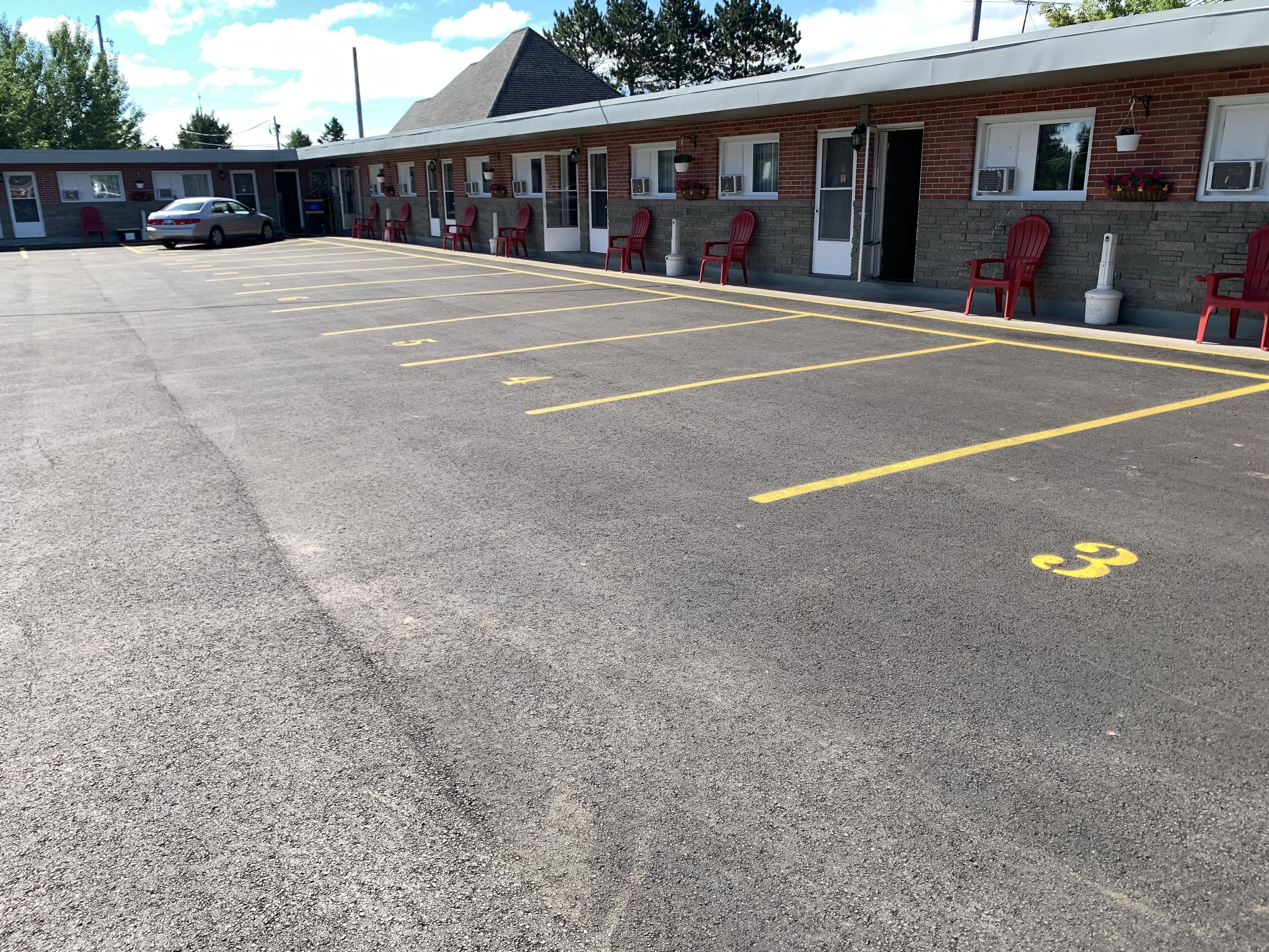 Un motel doté d’un parking délimité par des lignes jaunes et dont les places de stationnement sont numérotées.