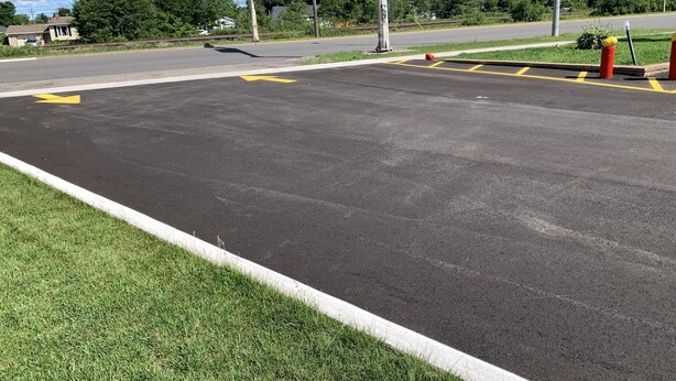 A parking lot with yellow directional arrows and a green sign indicating Sudbury. - Trunk Road Motel (Sault Ste. Marie)