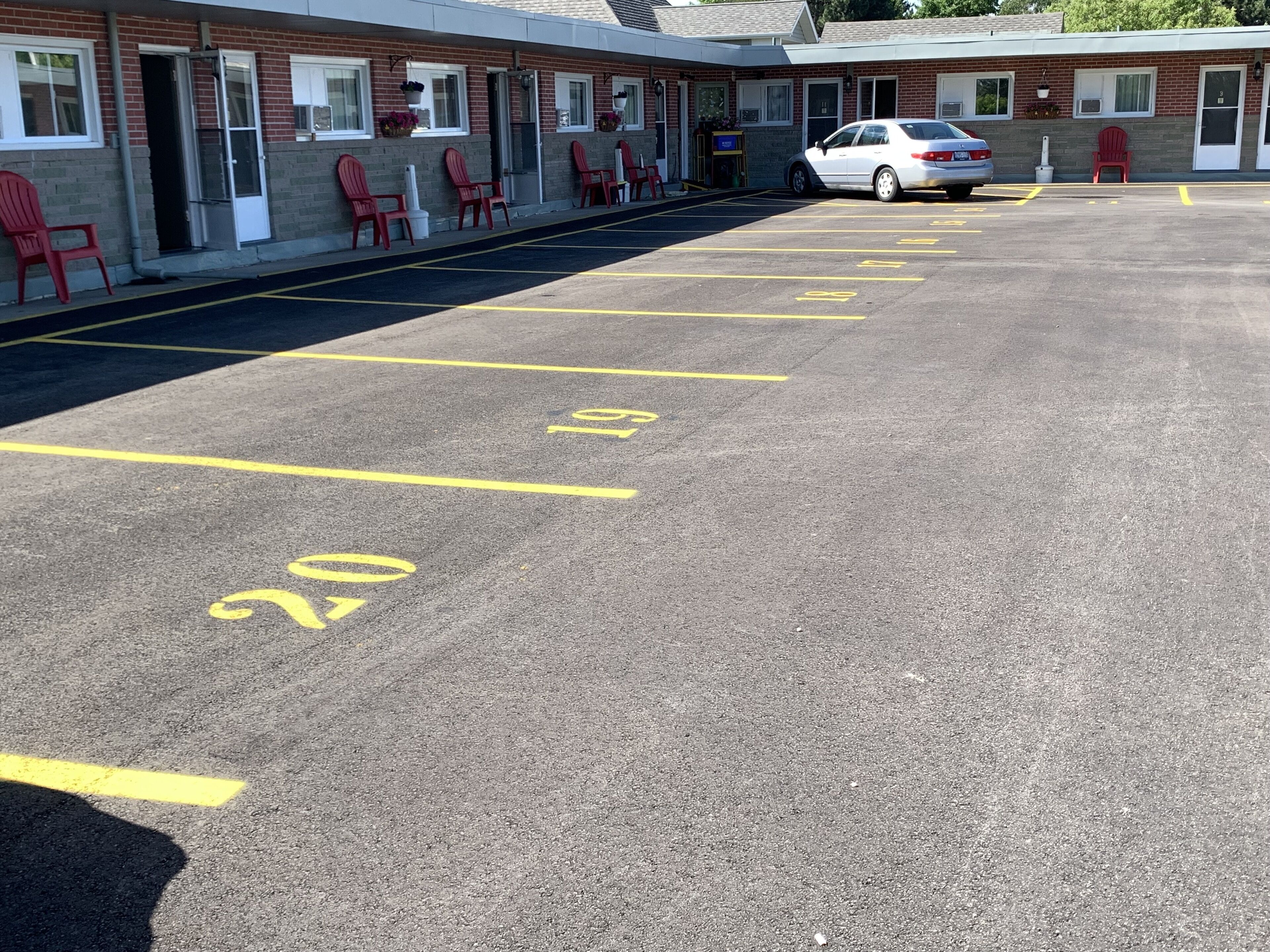 A parking lot with marked spaces and a building with red chairs outside.
