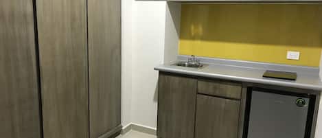 Cocina compacta con microondas, fregadero y nevera pequeña.