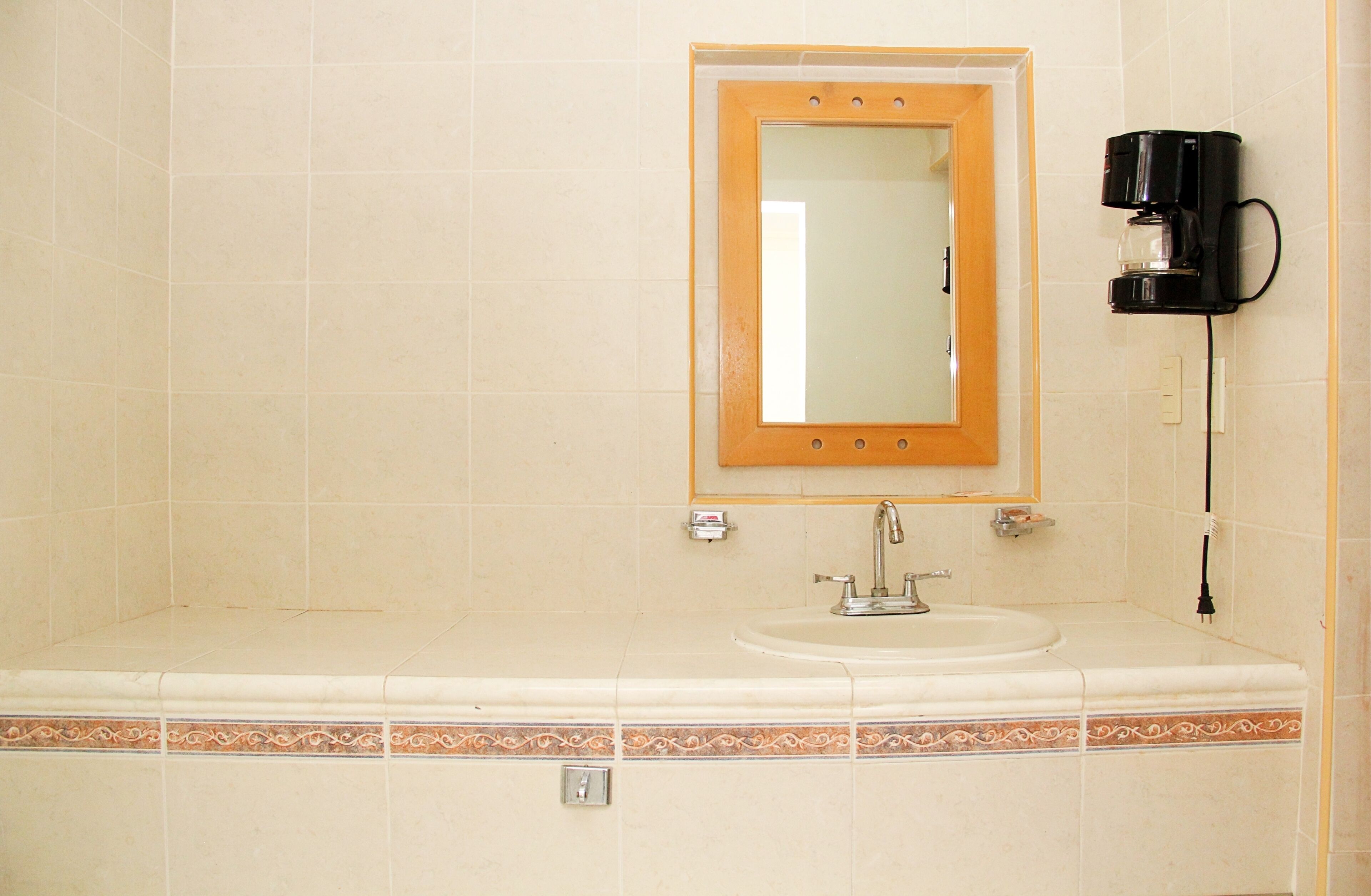 A bathroom with a sink, mirror, and coffee maker.