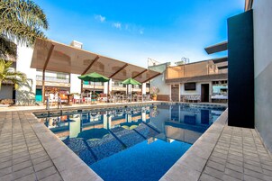 Una piscina al aire libre, sombrillas, sillones reclinables de piscina