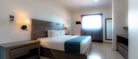 Quarto de hotel moderno com uma cama grande, mesas de cabeceira, escrivaninha e televisão.
