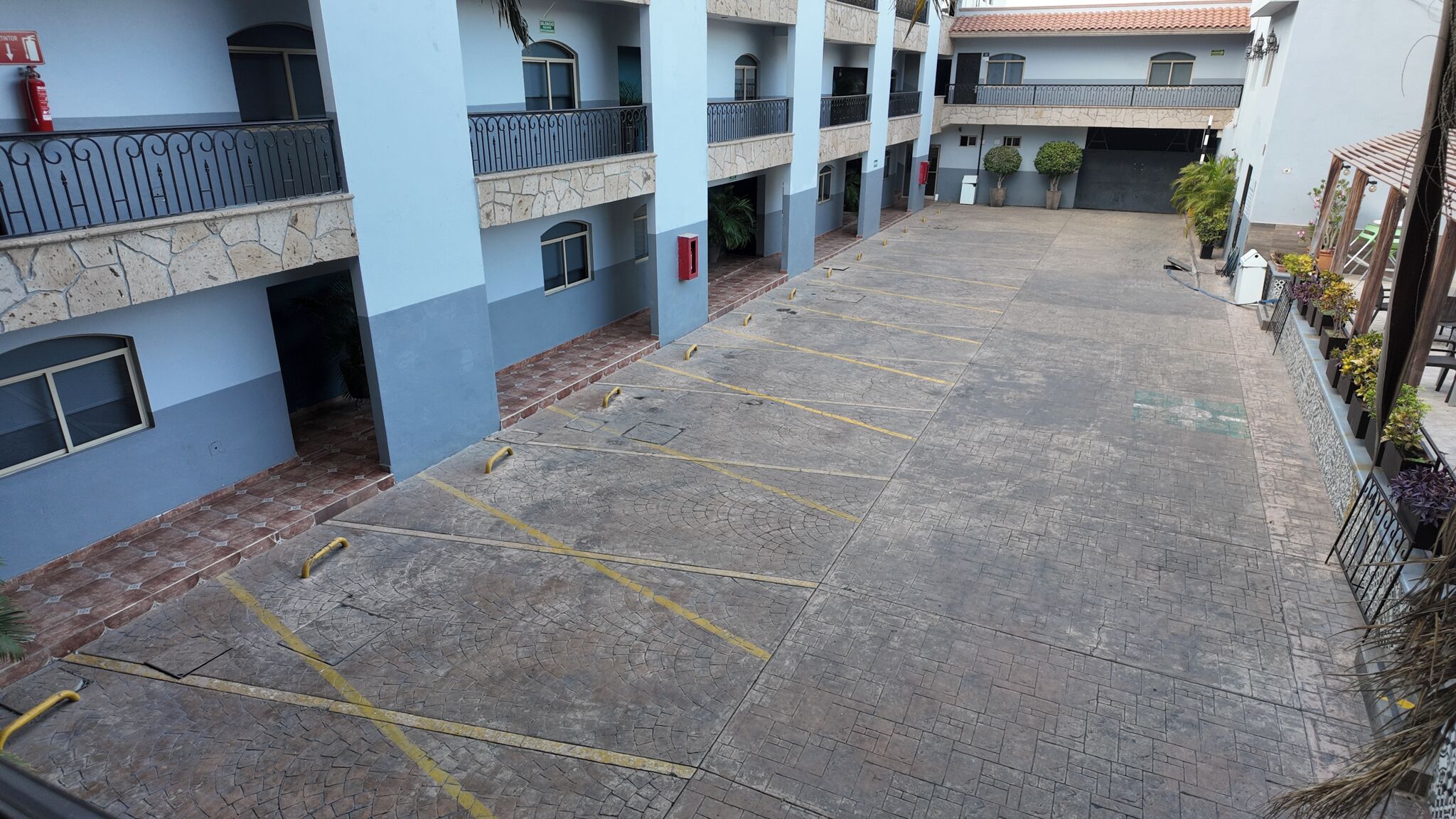 Un edificio de varios pisos con un patio que incluye una zona de estacionamiento.