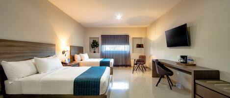 A hotel room with two beds, a desk, a chair, a TV, and a window with curtains.