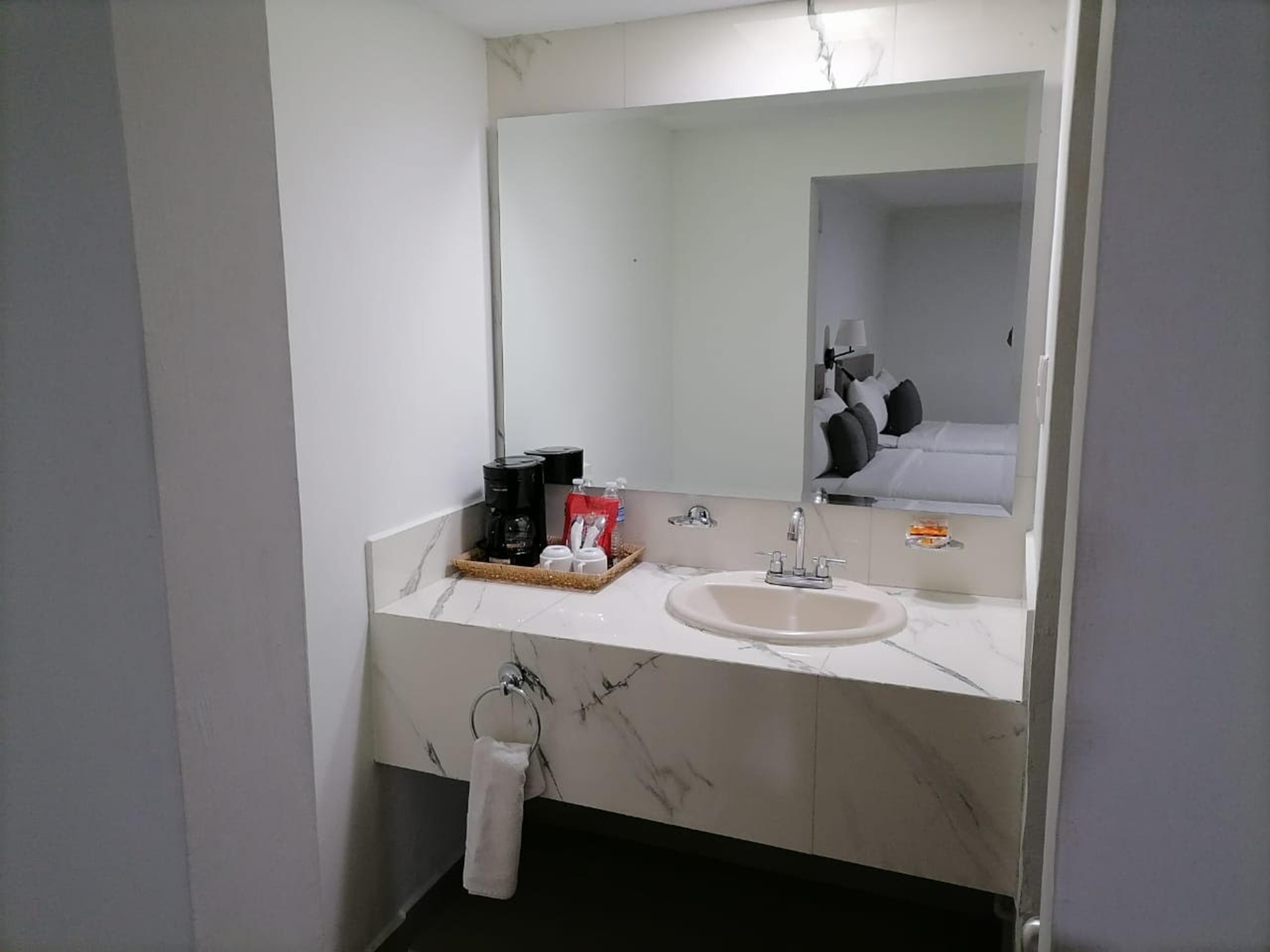 A bathroom with a marble sink, a coffee maker, and a towel ring.